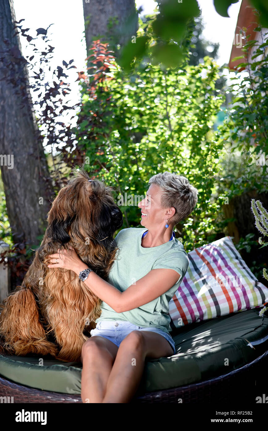 Lächelnde Frau mit ihrem Hund in den Garten Stockfoto