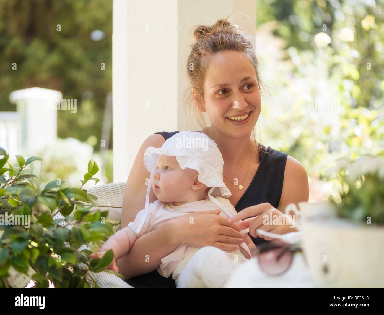 Portrait von entspannt Mutter mit Baby auf dem Schoß sitzen auf der Terrasse Stockfoto