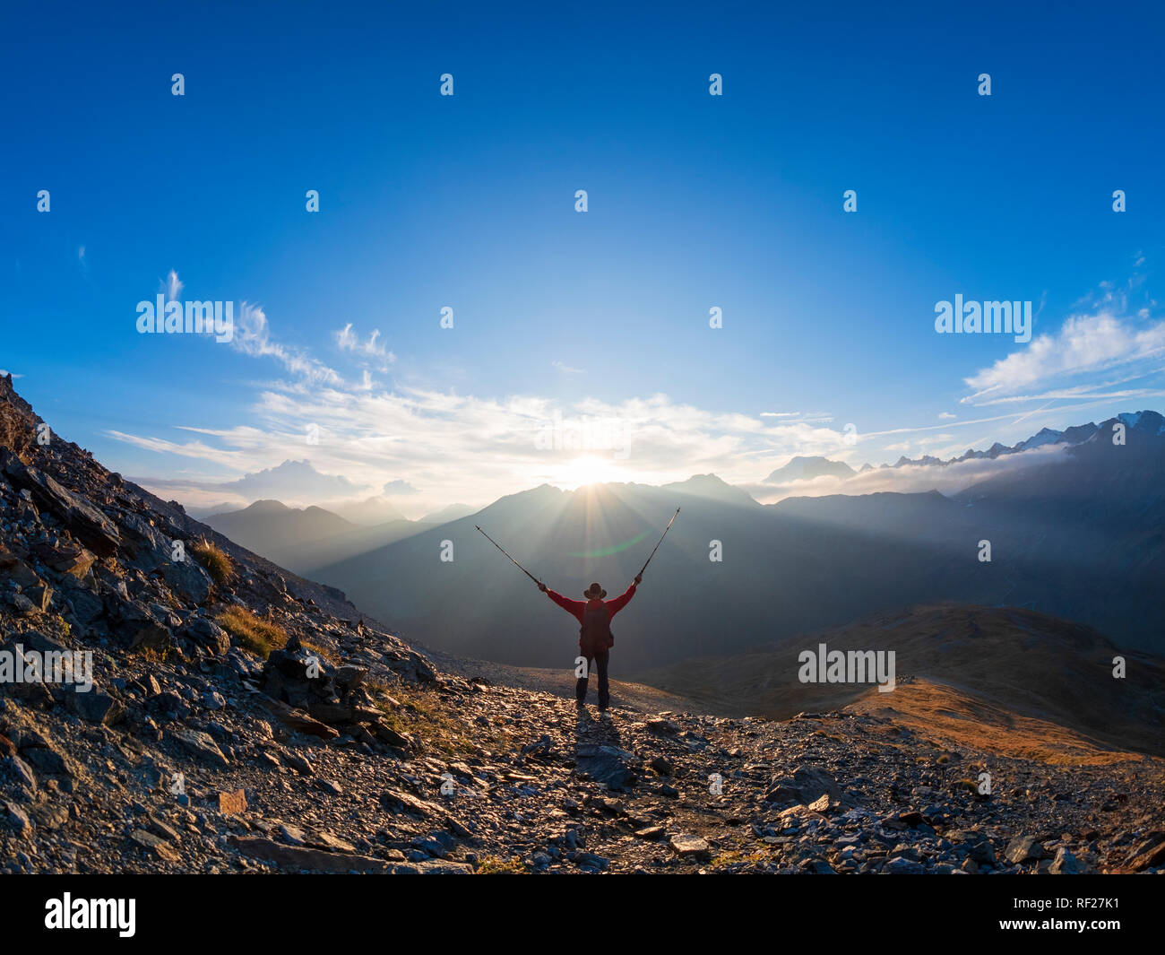 Grenzregion Italien Schweiz, jubelnde älterer Mann mit Wanderstöcken in Berglandschaft am Piz Umbrail-pass Stockfoto