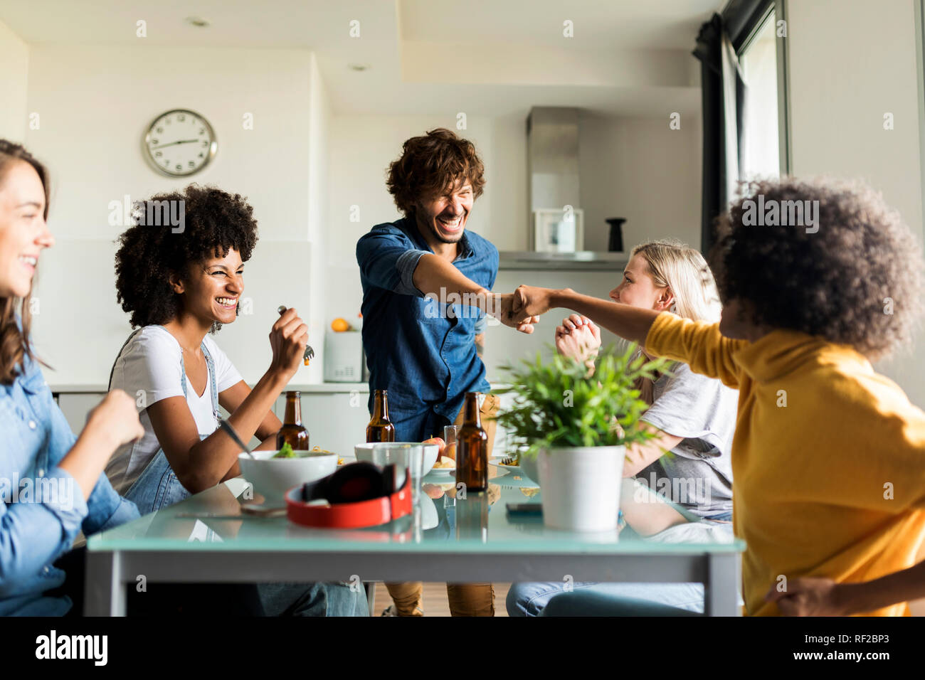 Fröhliche Freunde am Esstisch sitzen Stockfoto