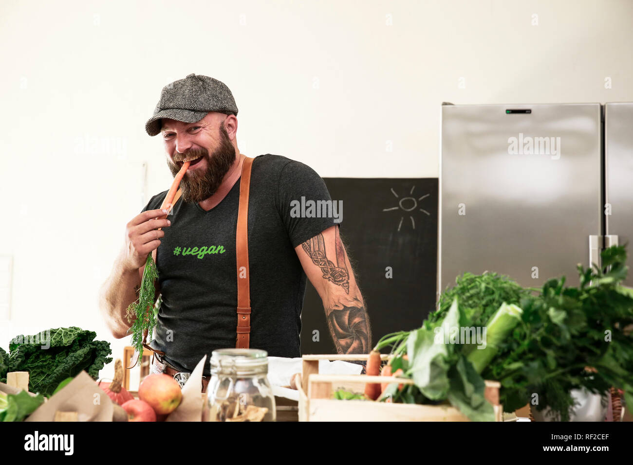 Vegan mann Heizung Karotte in seiner Küche Stockfoto