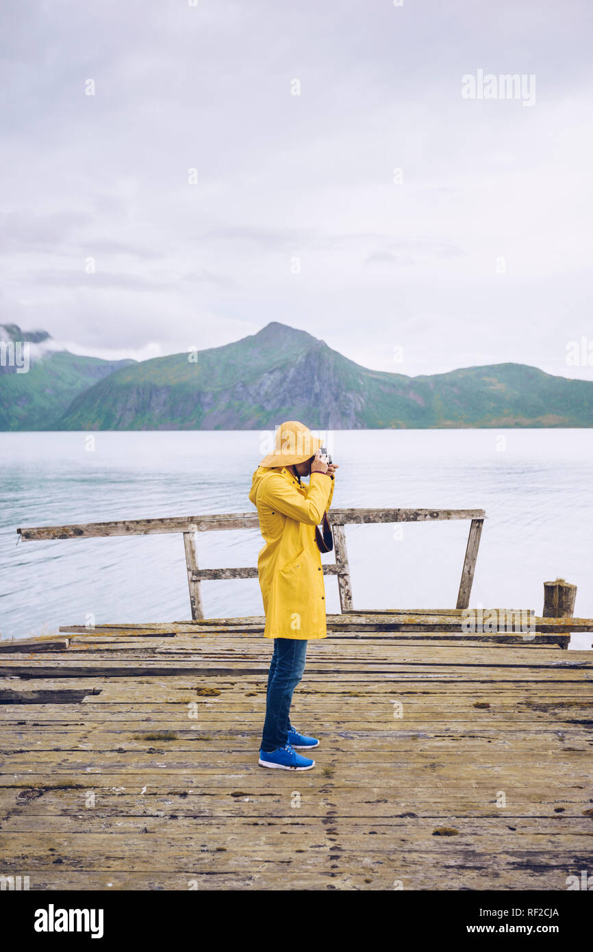 Norwegen, Senja, Mann, stehend auf einem maroden Mole an der Küste ein Bild aufnehmen Stockfoto