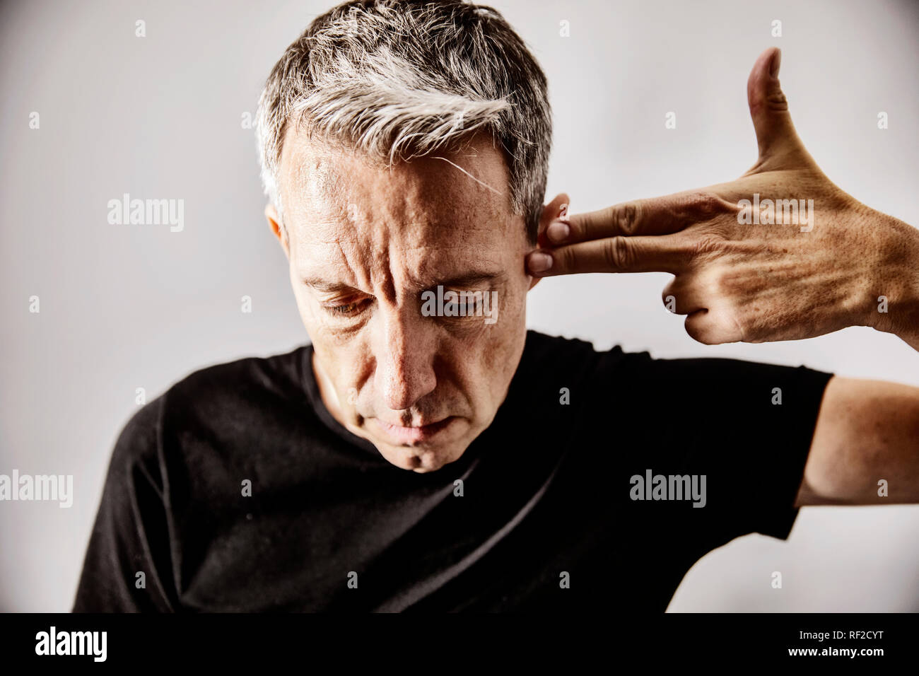 Portrait von reifer Mann zu schießen Geste mit seiner Hand gegen seinen Tempel Stockfoto