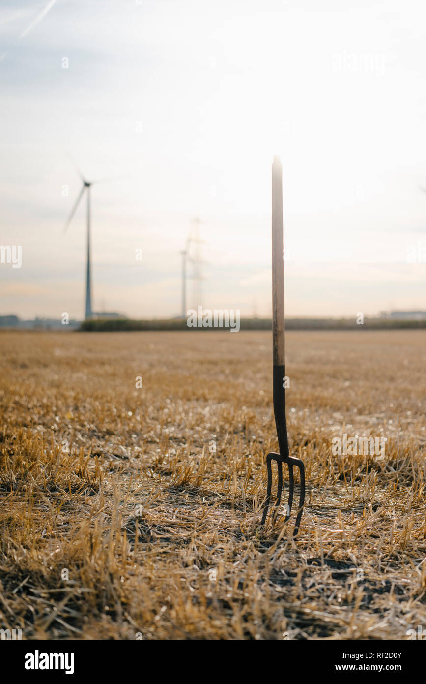 Pitchfork im Feld in ländlichen Landschaft mit Windkraftanlagen im Hintergrund Stockfoto