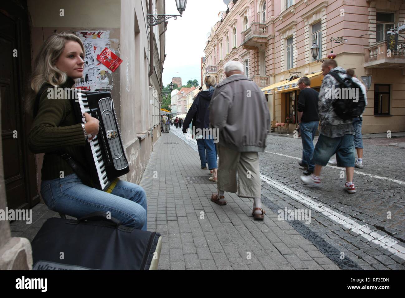 Akkordeon spielen junge blonde Frau Straßenmusiker und Fußgänger in der Altstadt von Vilnius, die Hauptstadt von Litauen Stockfoto