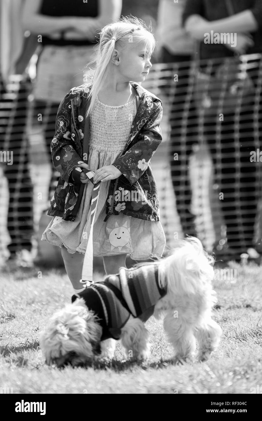 Ein kleines Mädchen zu Fuß zu ihrem Hund im Park auf einer Hundeausstellung Stockfoto