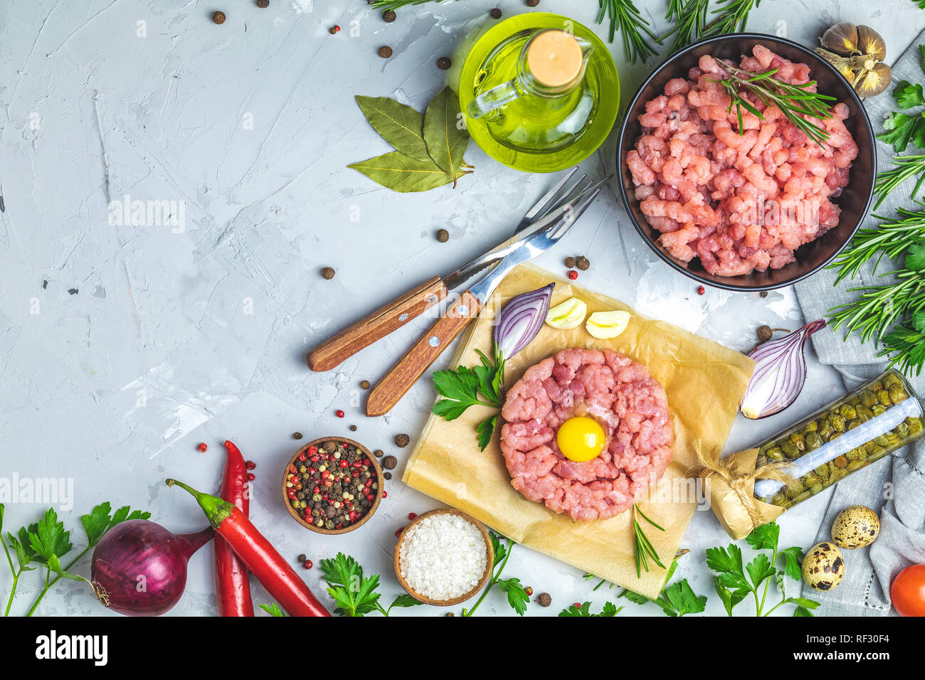 Gesundes Essen, kochen Konzept. Hausgemachte organischen Fleisch Hackfleisch und Tatar mit Eigelb mit Gemüse auf hellen grauen Stein Beton texturiert Stockfoto