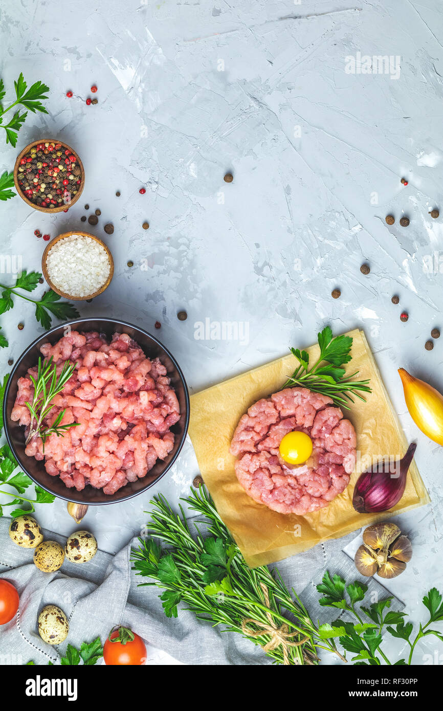 Gesundes Essen, kochen Konzept. Hausgemachte organischen Fleisch Hackfleisch und Tatar mit Eigelb mit Gemüse auf hellen grauen Stein Beton texturiert Stockfoto