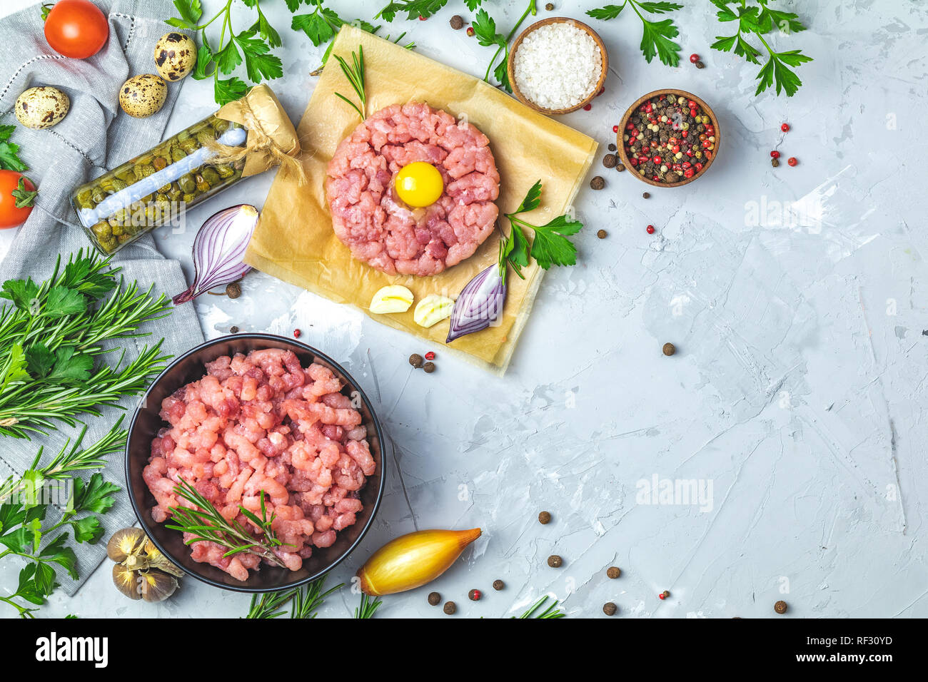 Gesundes Essen, kochen Konzept. Hausgemachte organischen Fleisch Hackfleisch und Tatar mit Eigelb mit Gemüse auf hellen grauen Stein Beton texturiert Stockfoto