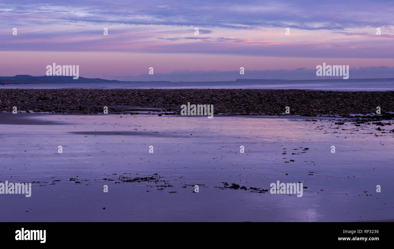 Charmouth, Dorset, Großbritannien. 23. Januar 2019. UK Wetter: Ein kalter Winter Abend am Meer Dorf Charmouth, Dorset. Der Himmel mit Blick auf den Golden Cap und der Jurassic Coast sind mit winterlichen rosa getönt wie die Sonne an einem kalten Januar Abend einstellt. Credit: Celia McMahon/Alamy leben Nachrichten Stockfoto