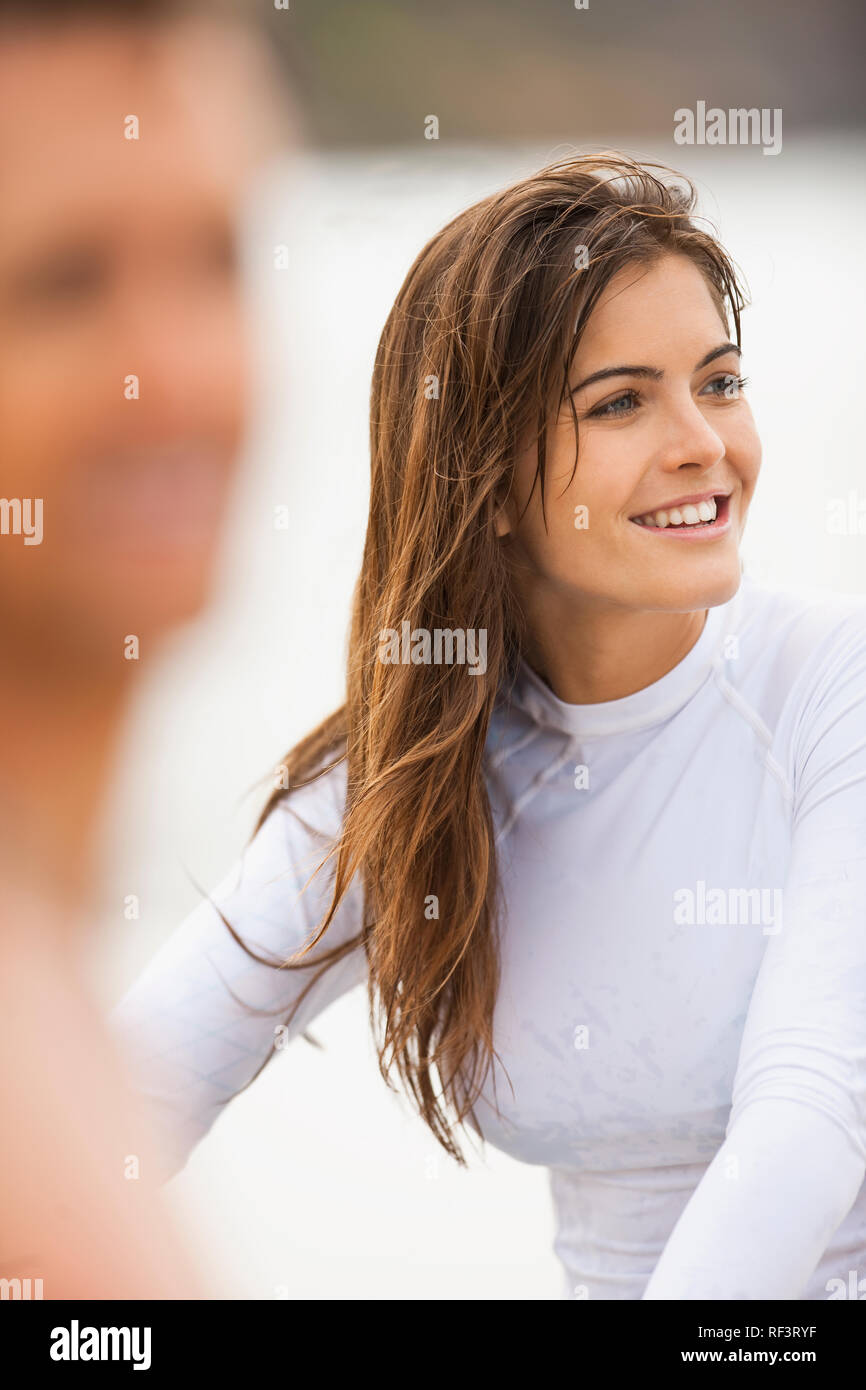Junge Frau am Strand, mit ihrem Freund im Vordergrund, unscharf. Stockfoto