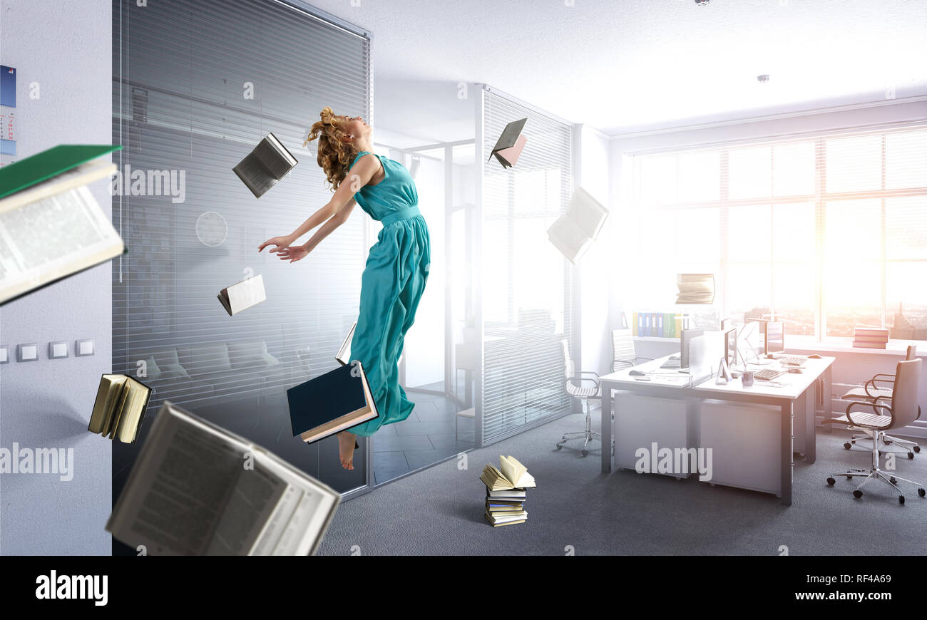Junge Frau in Kleid schweben in der Luft unter Bücher und Gegenstände. Mixed Media Stockfoto