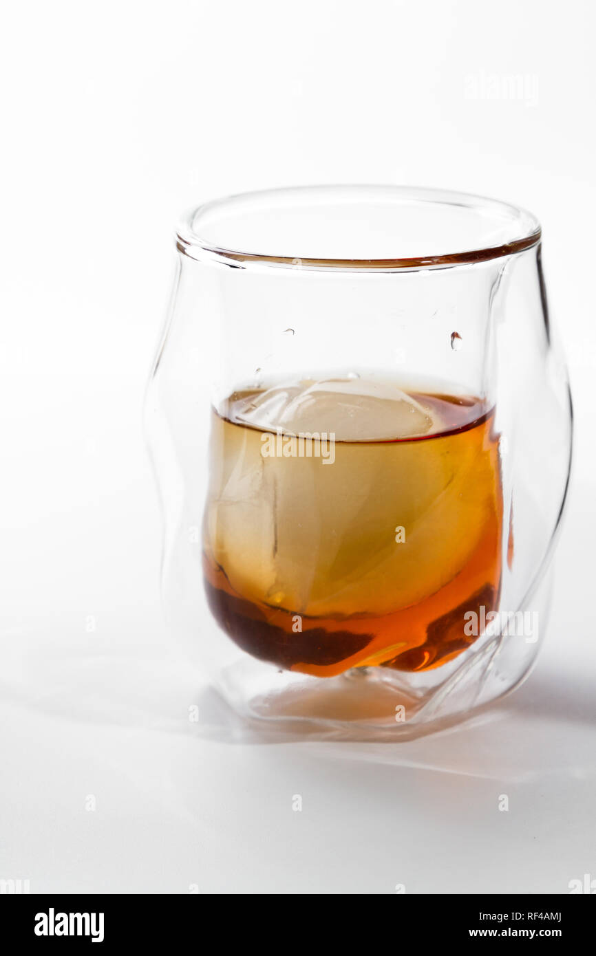 Bourbon serviert in einem doppelwandigen Whisky Glas mit Eis Kugel über einen weißen Hintergrund serviert. Stockfoto
