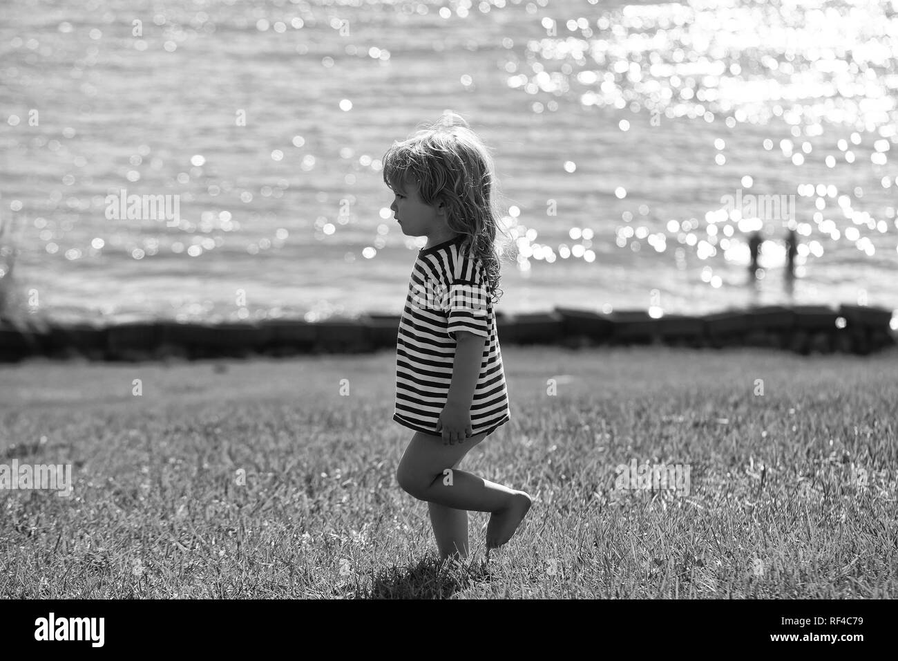 Cute Baby boy in gestreiften T-Shirt Spaziergänge auf grünem Gras Stockfoto