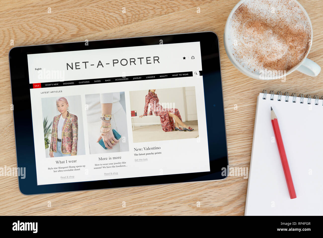 Die Net-a-Porter-Website bietet auf einem iPad Tablet Gerät, das auf einem Tisch liegt neben einem Editor (nur redaktionell). Stockfoto