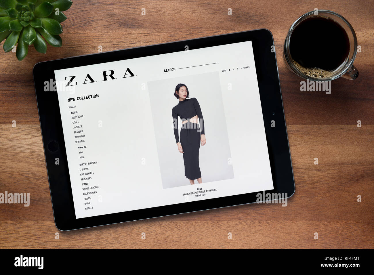 Die Website von Zara ist auf einem iPad Tablet gesehen, auf einer hölzernen Tisch zusammen mit einem Espresso und einem Haus Anlage (nur redaktionelle Nutzung). Stockfoto