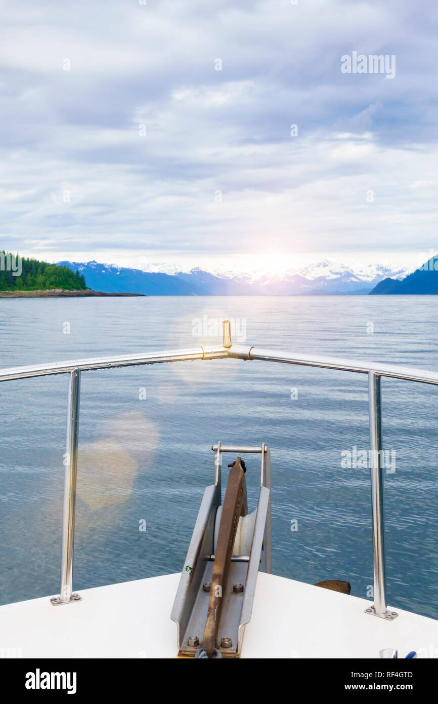 Motor Crusing Yacht in der Glacier Bay National Park, Alaska. Sonnenuntergang Blick auf fernen Inseln und die schneebedeckten Berge der Bogen ein Motorboot. Stockfoto