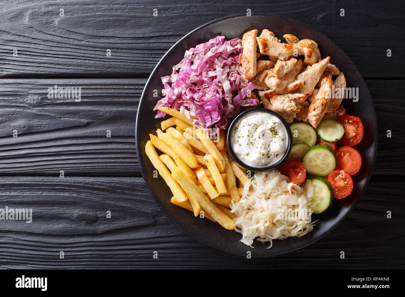 Döner auf einem Teller mit Pommes frites, Salat und Sauce close-up auf einem Holztisch. Horizontal oben Ansicht von oben Stockfoto