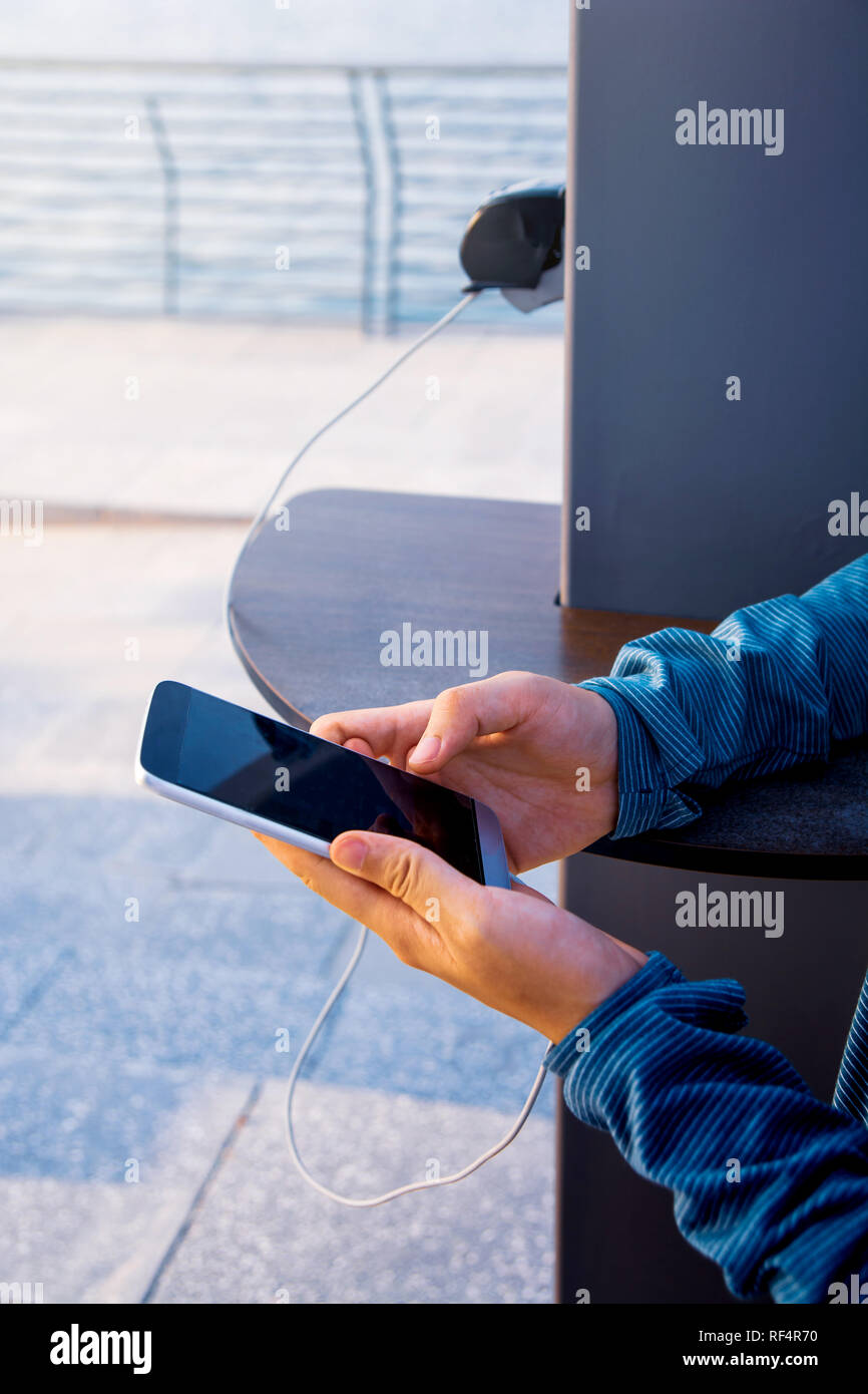 Weibliche mit Telefon und Laden auf einer öffentlichen Ladegerät Stockfoto