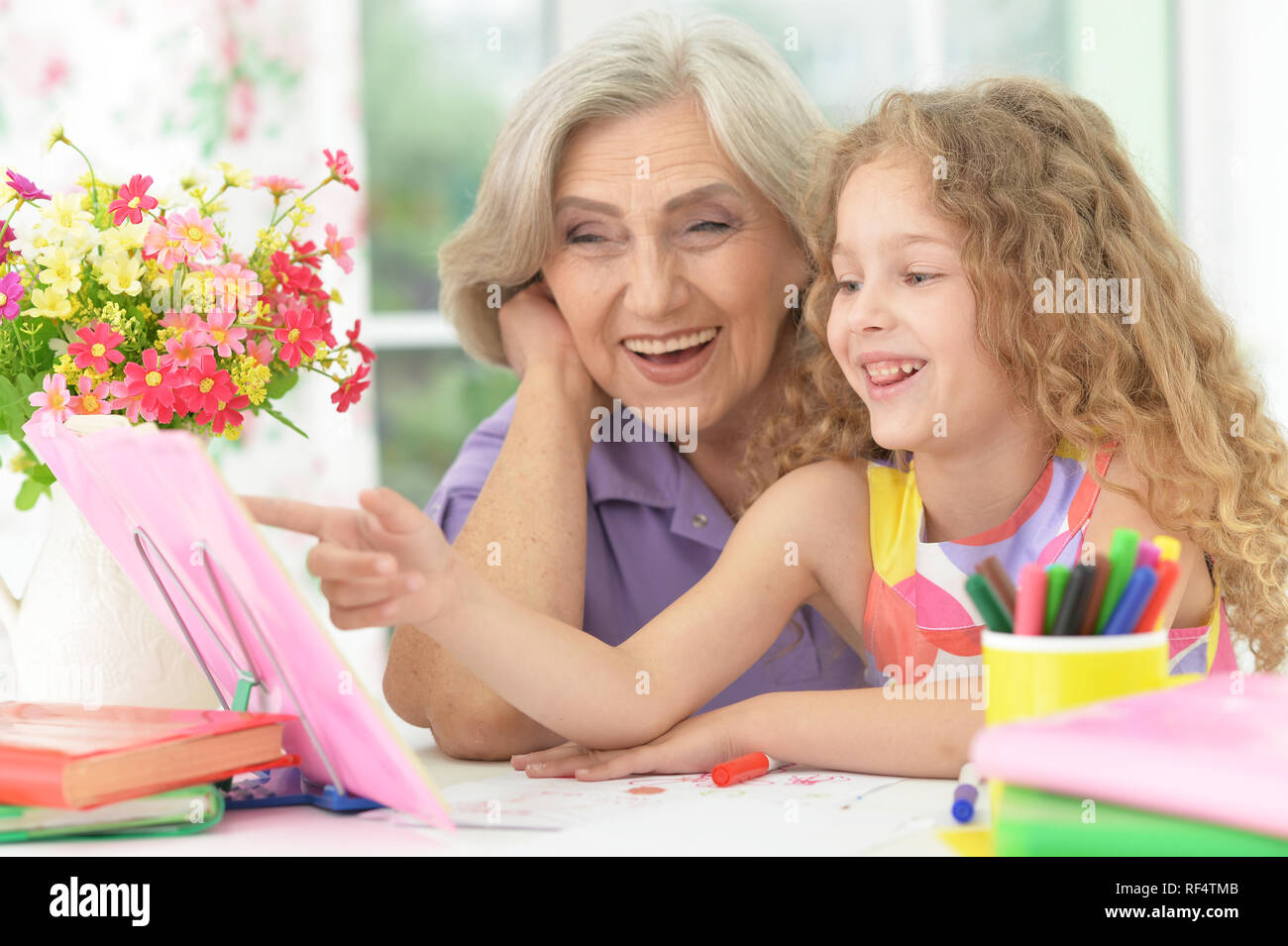 Portrait von Schulmädchen studieren mit Großmutter zu Hause Stockfoto