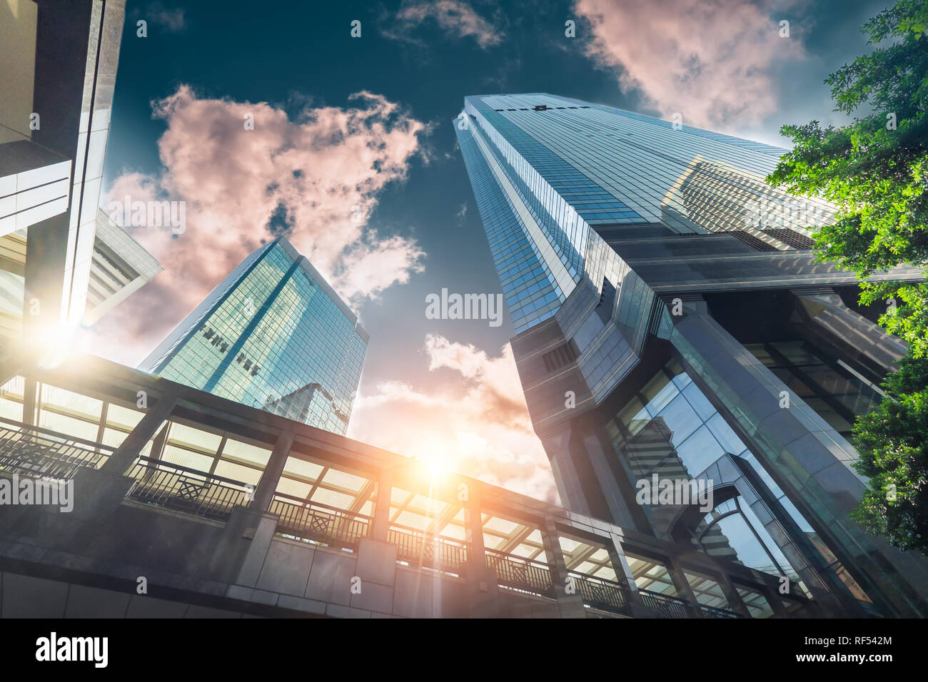Abstrakte futuristische Stadtlandschaft mit modernen Wolkenkratzern. Sonne in den Sonnenuntergang Himmel, im Glas von der Fußgängerbrücke zu reflektieren. Die städtische Architektur ba Stockfoto