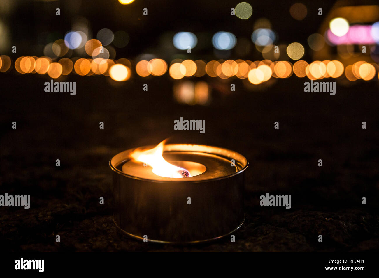 Selektiver Fokus auf einer beleuchteten Outdoor Kerze (auch bekannt als pitch Taschenlampe oder einen Garten Kerze), eine Menge von Kerzen brennen auf dem Hintergrund an der Nahe. Stockfoto