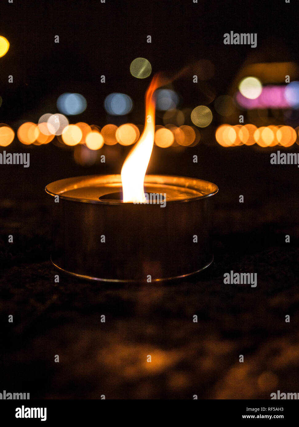 Selektiver Fokus auf einer beleuchteten Outdoor Kerze (auch bekannt als pitch Taschenlampe oder einen Garten Kerze), eine Menge von Kerzen brennen auf dem Hintergrund an der Nahe. Stockfoto