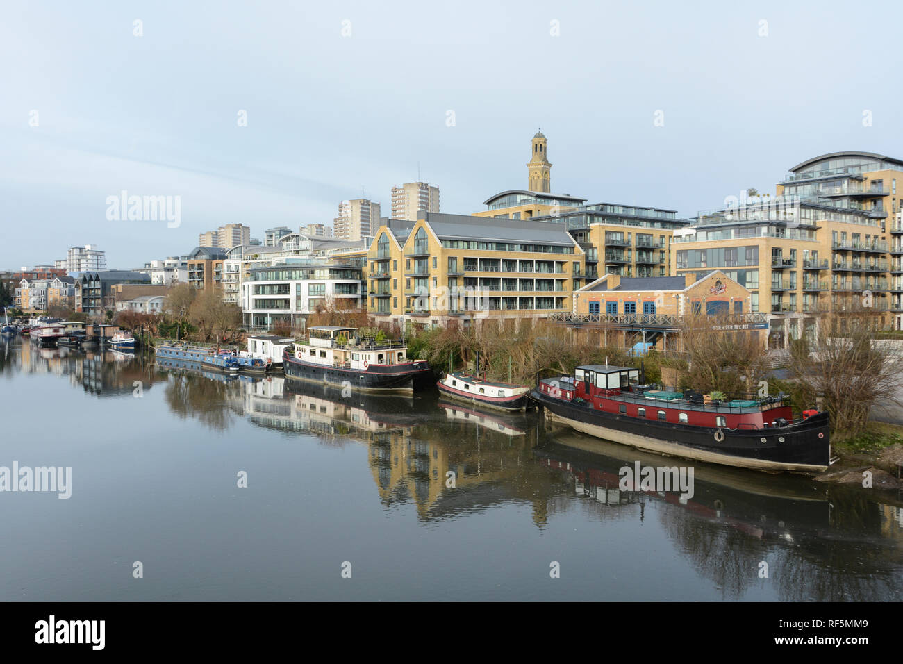 Hausboote auf der Themse mit dem neuen Kew Bridge Road, das Entwicklung in den Vordergrund und Brentford Türme Wohnsiedlung im Hintergrund Stockfoto