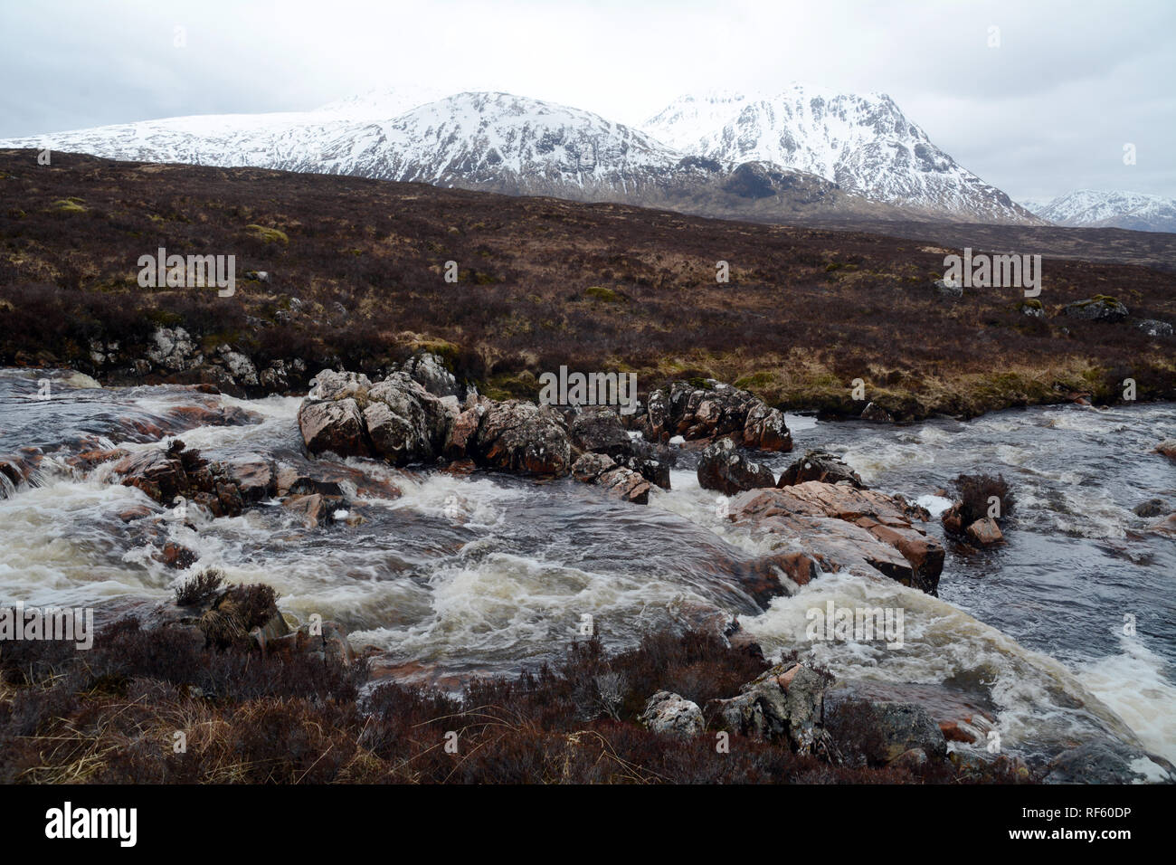 Der Fluss Etive mit den schneebedeckten Gipfeln der Schottischen Highlands im Hintergrund, Glencoe, Schottland, Vereinigtes Königreich. Stockfoto