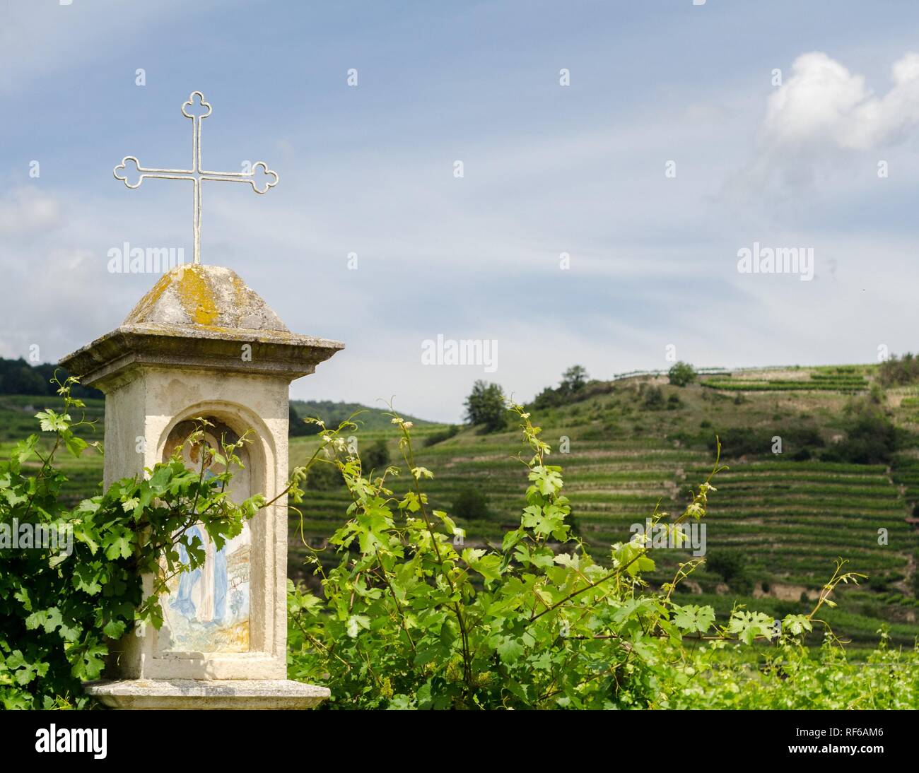 Eine kleine religiöse Denkmal auf dem Donauradweg. Die Berge im Hintergrund sind für die Landwirtschaft terrassiert. Stockfoto