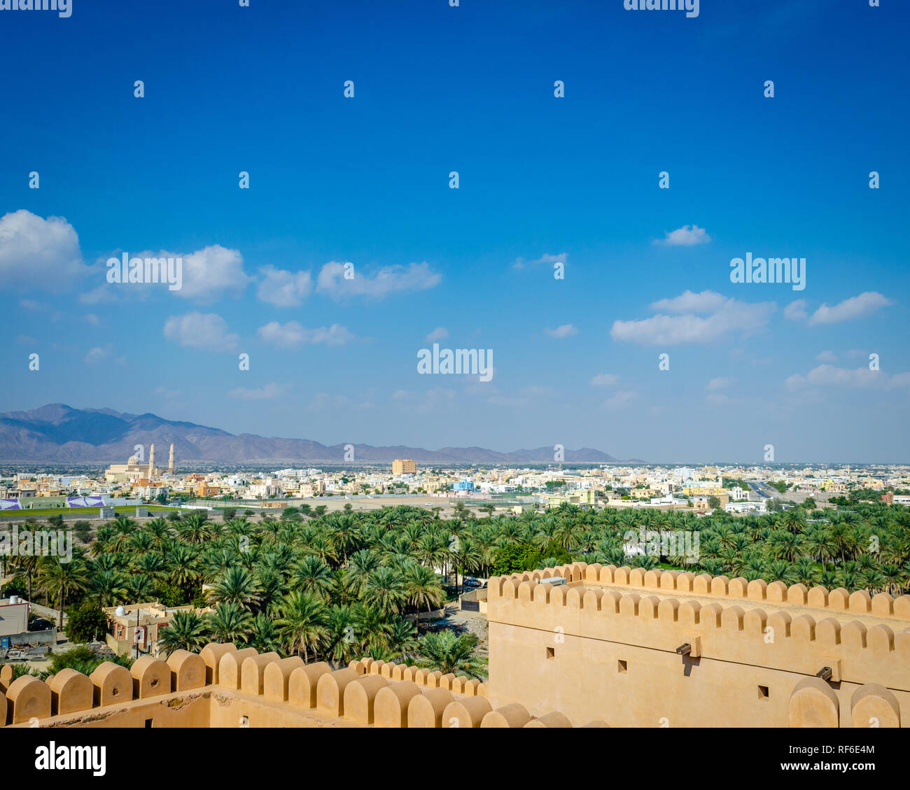 Oase in der Wüste, Barka Township und die Berge in der Ferne gesehen von der Terrasse der Nakhal Fort, Muscat, Oman. Stockfoto
