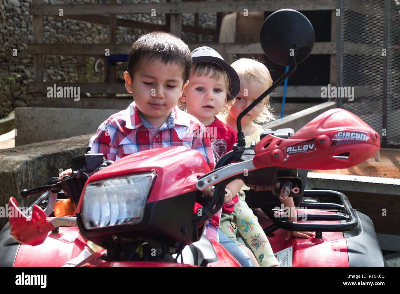 Ein Foto der drei Kinder (zwei Jungen und ein Mädchen) spielen Mit einem Honda ATV Stockfoto