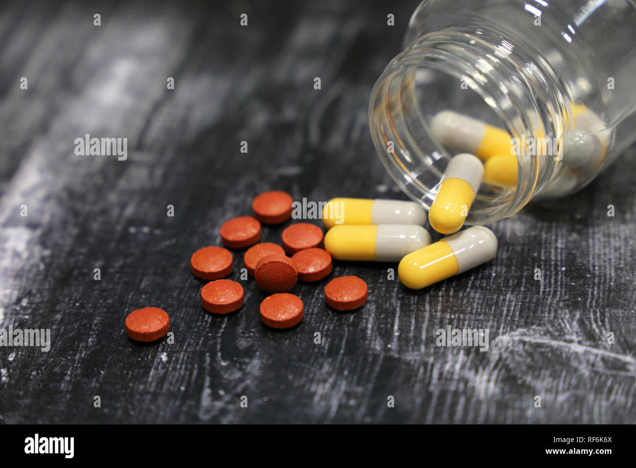 Pillen und Kapseln in transparente Flasche auf dunklen Holztisch. Konzept von Drogen, Antibiotika, Vitamine, die gleichzeitige Stockfoto
