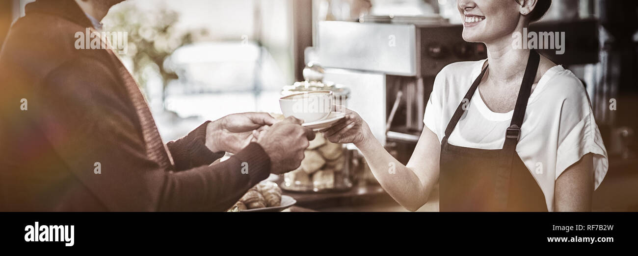 Kellnerin serviert eine Tasse Kaffee an Kunden Stockfoto