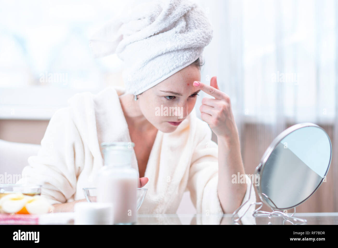 Schöne unglückliche junge Frau mit einem Handtuch auf dem Kopf erkennt Akne im Gesicht. Konzept der Hygiene und Pflege für die Haut Stockfoto