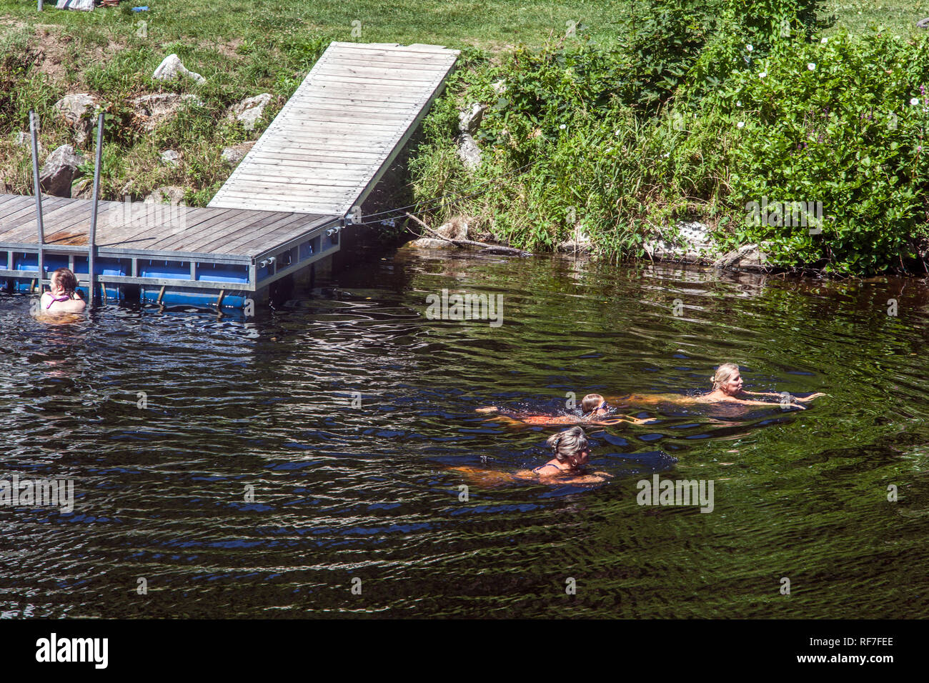 Vier Frauen schwimmen im Fluss Otava, in der Nähe eines hölzernen Pier, Südböhmen, Tschechische Republik Stockfoto
