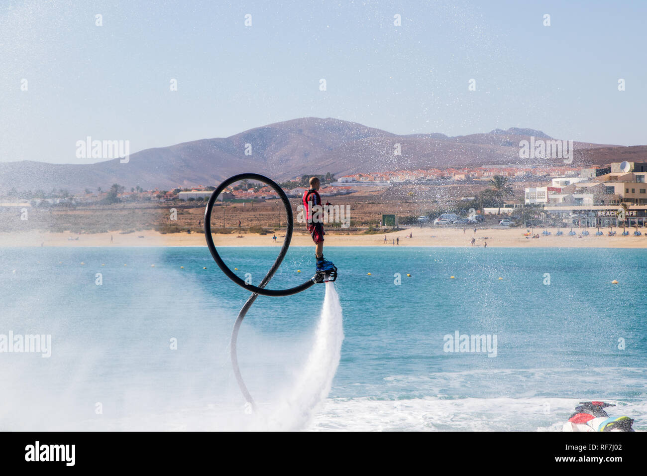 Fuerteventura, Spanien - Januar 12, 2019: ein Mann tut, Akrobatik mit flyboard zu Jet ski in der Nähe des Hafens in Caleta de Fuste, Fuerteven Stockfoto