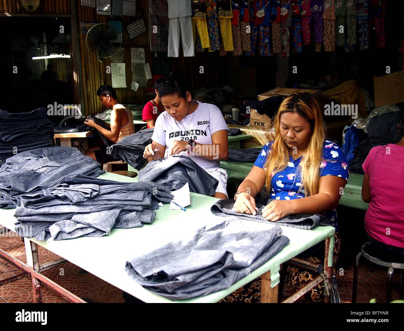 ANTIPOLO CITY, Philippinen - Januar 7, 2019: Schneider zu einem Kleidung Manufacturing Company, der letzte Schliff auf langen Jeans. Stockfoto