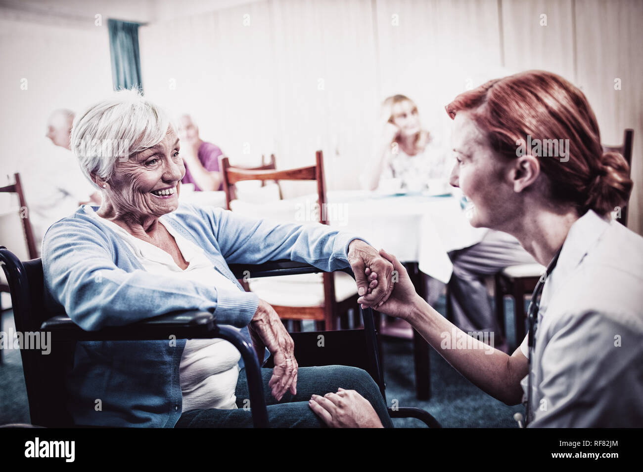 Krankenschwester, die Interaktion mit einer älteren Frau im Rollstuhl Stockfoto