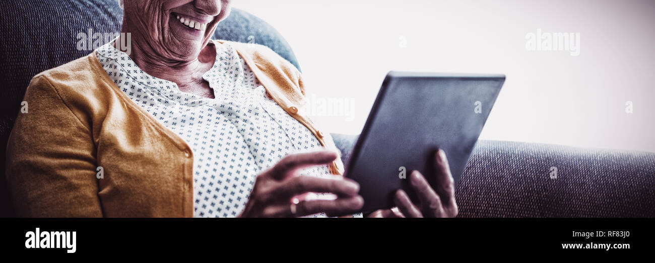 Lächelnde senior Frau auf der Suche und lachen über ihre digital-Tablette Stockfoto