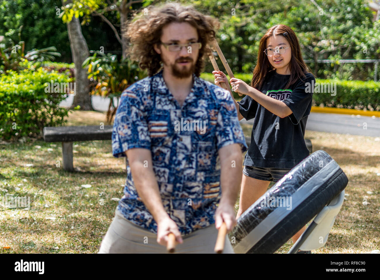 Ein Lehrer und ein Schüler spielen eine japanische taiko Drum eines alten Reifen und Klebeband. In einem schönen grünen Park fotografiert. Stockfoto