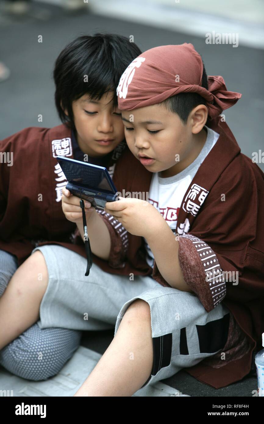 Japan, Tokio: Heiligtum Festival, genannt Matsuri. Kinder spielen mit einem tragbaren Computer Spiel. Stockfoto