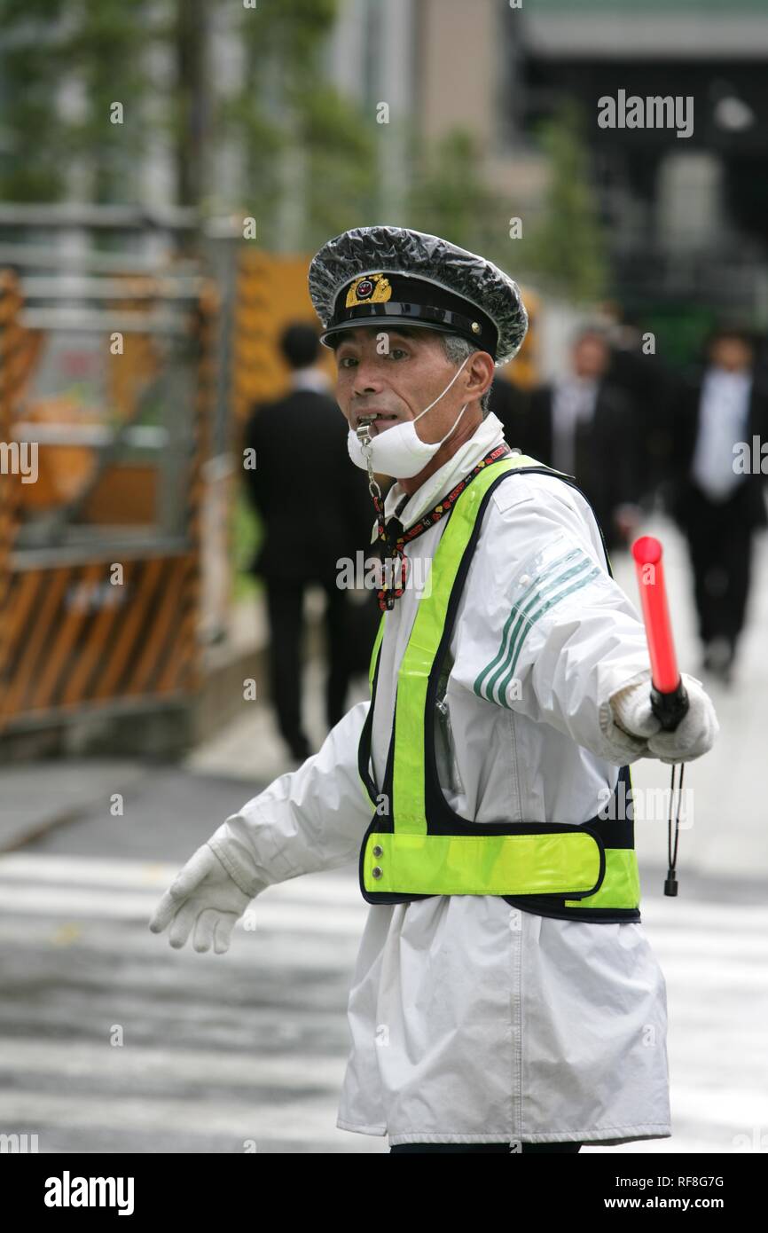 Verkehr Offizier leitet den Datenverkehr an einem Gebäude Eingang, Tokio, Japan, Asien Stockfoto