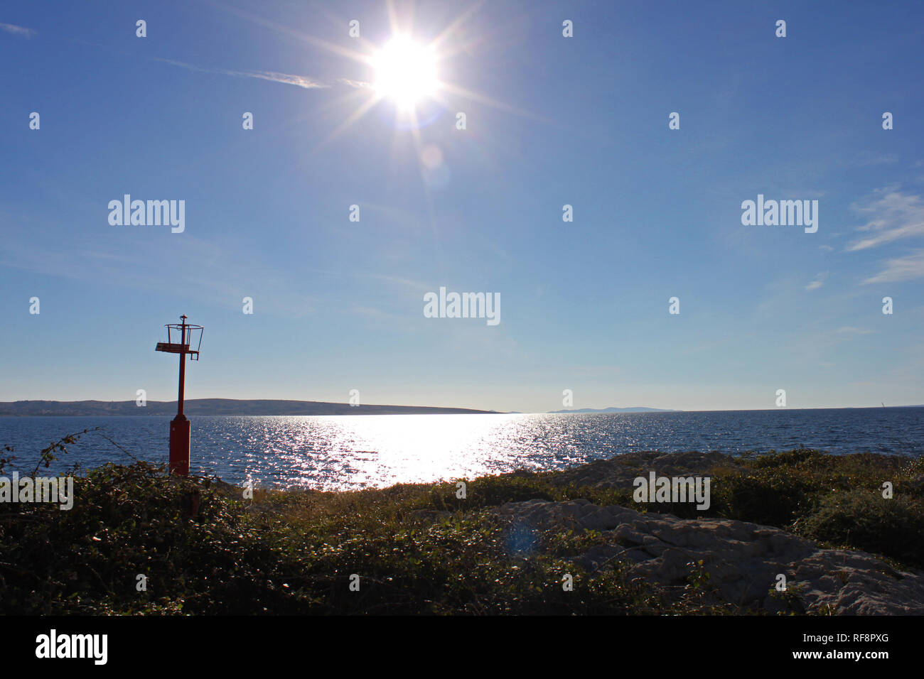 Küste am Kukljica Strand mit einem kleinen Leuchtturm. Sun hoch in den Himmel. Kukljica Strand auf der Insel Pag, Kroatien. Stockfoto