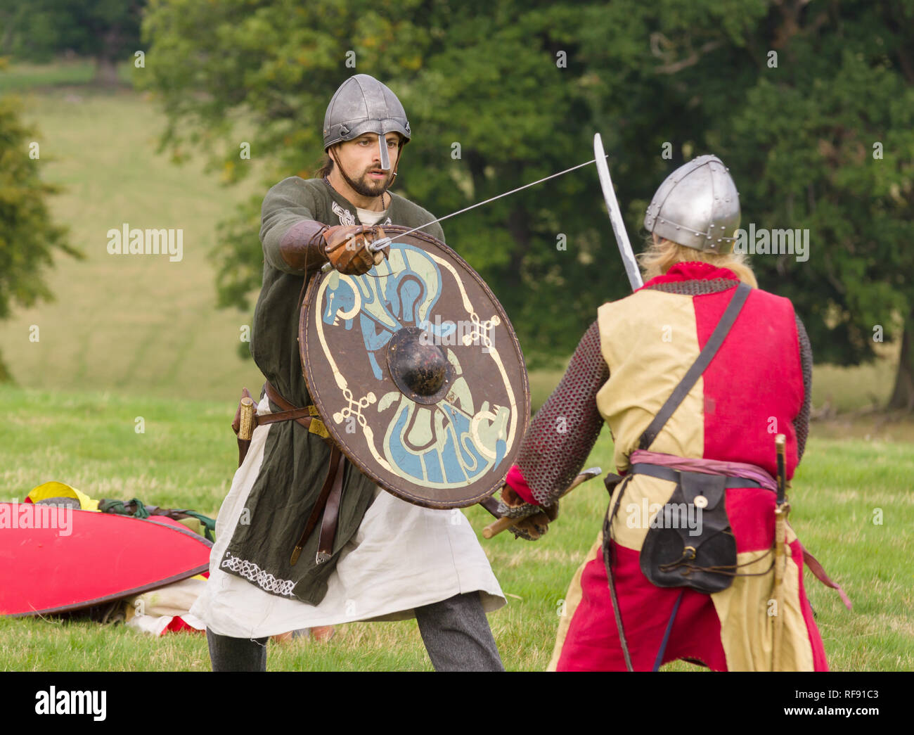 Mittelalterliche Re-enactors in Rüstung und Kostüme des 12. Jahrhunderts mit Waffen ausgestattet gekleidet nachgespielt Bekämpfung des Zeitraums Stockfoto