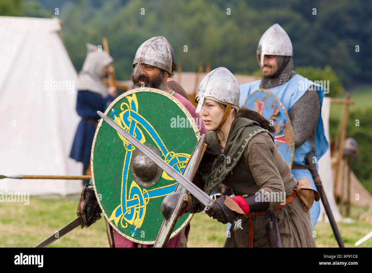 Mittelalterliche Re-enactors in Rüstung und Kostüme des 12. Jahrhunderts mit Schwertern und Schilden ausgestattet gekleidet nachgespielt Bekämpfung des Zeitraums Stockfoto