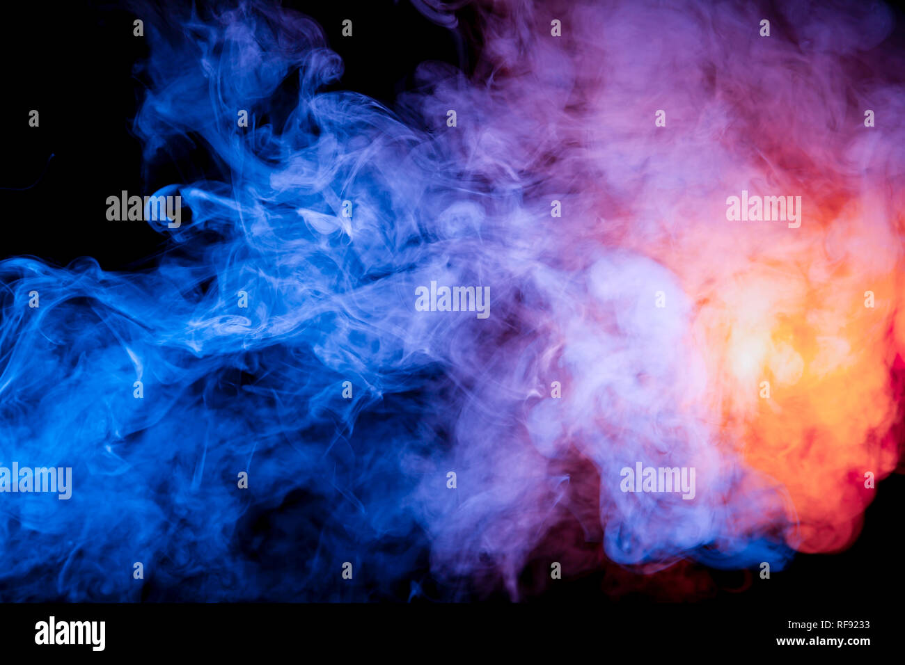 Mehrfarbige Rauch wie kosmischer Staub von Blau, Rot, Magenta und Fiery orange auf einem schwarzen Hintergrund ist in Ringen umwickelt. Stockfoto