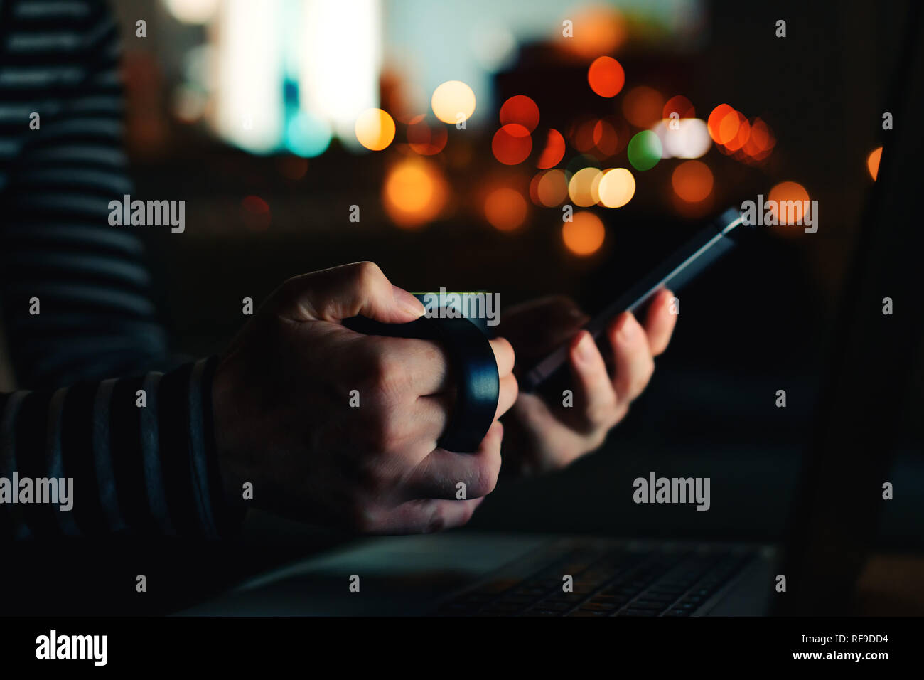 Frau mit Kaffee Tasse auf Bildschirm des Smartphones bei Nacht von Hand schließen Stockfoto