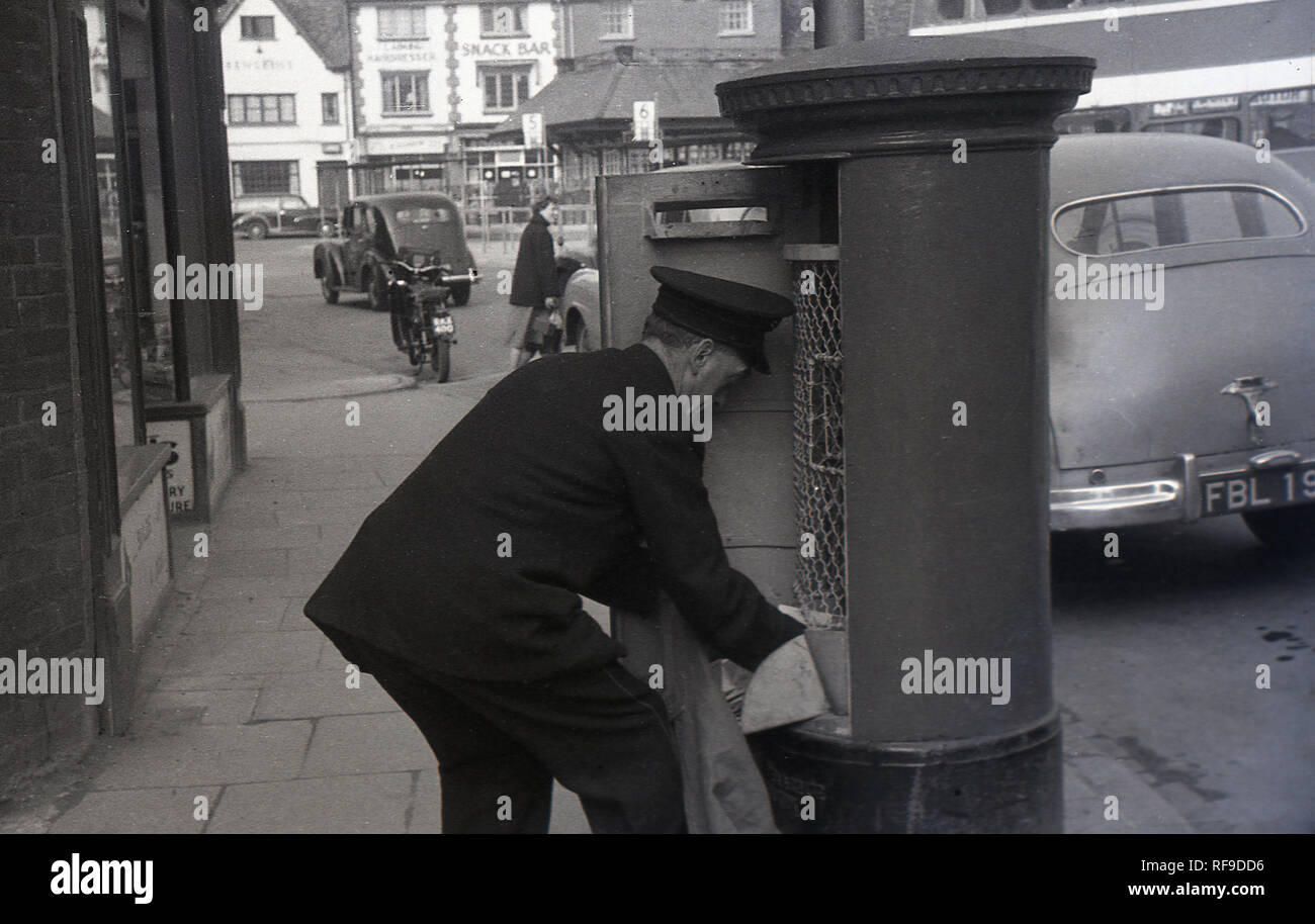 1950, historische, GPO Briefträger tragen Cap beim Entleeren eines High Street Post Box, England, UK. Stockfoto