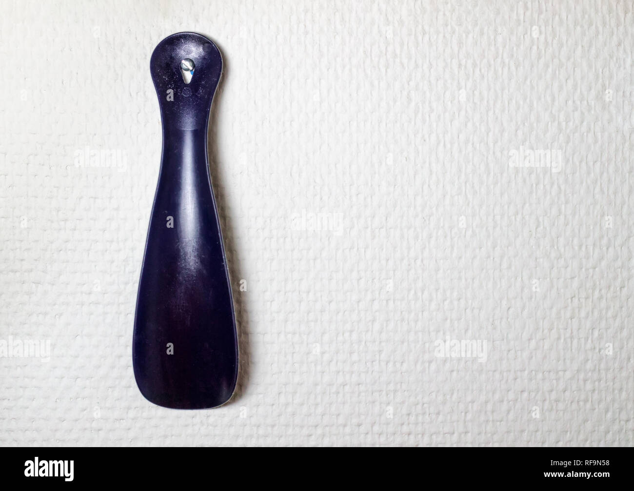 Dunkelblau Kunststoff Schuhlöffel in weiße strukturierte Wand Stockfoto